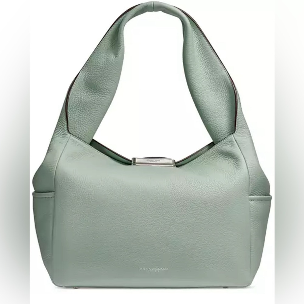 Crafted in leather with a signature curved closure shoulder bag by Donna Karan